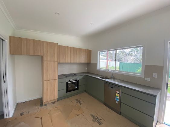 A Kitchen with Wooden Cabinets, a Stove, a Sink, and A Window — Lakesway Plumbing and Gas in Forster, NSW
