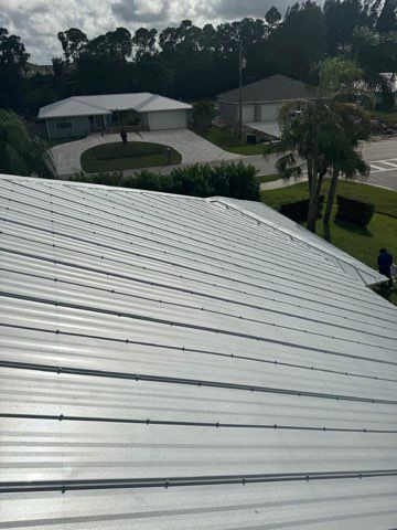 An aerial view of a metal roof with a house in the background.