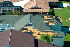 An aerial view of a house with a roof that is missing shingles