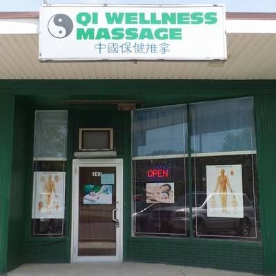 A green building with a sign that says qi wellness massage