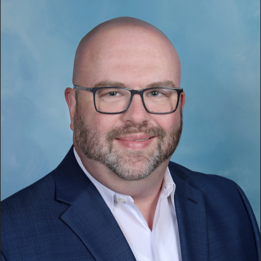 A bald man with a beard wearing glasses and a blue suit