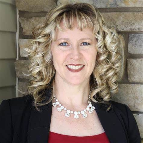 A woman with curly hair is wearing a pearl necklace and a black jacket.