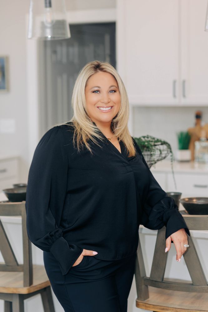A woman in a blue dress and white jacket is leaning on a railing.