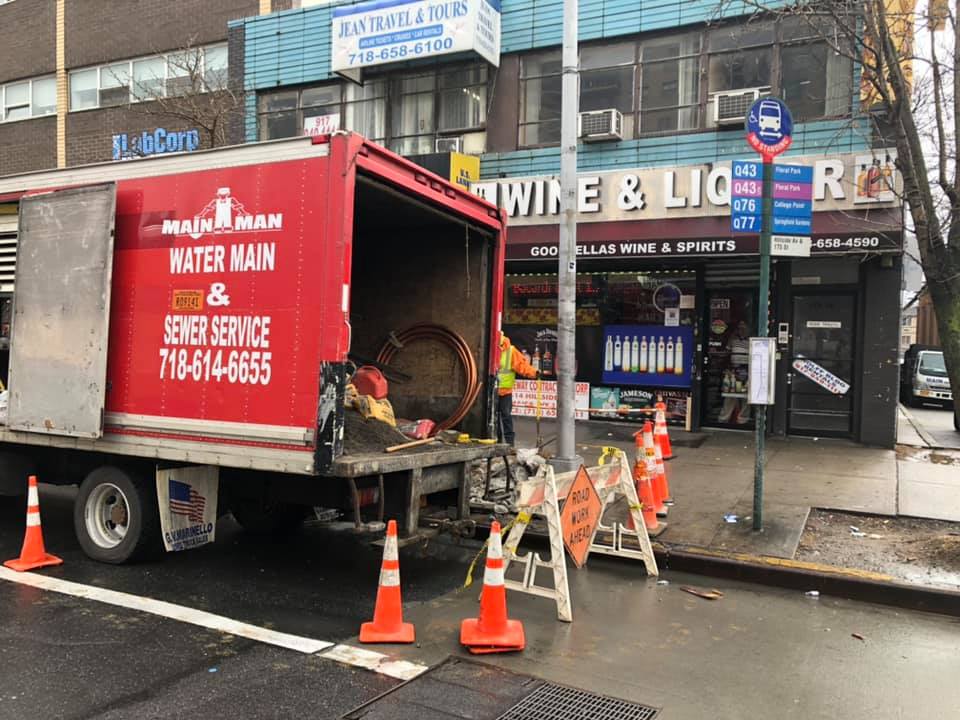 A red truck is parked on the side of the road in front of a wine and liquor store.