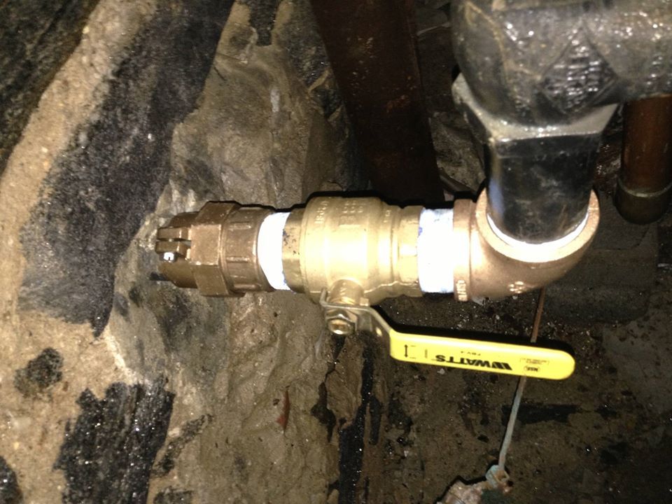 A yellow ball valve is attached to a pipe