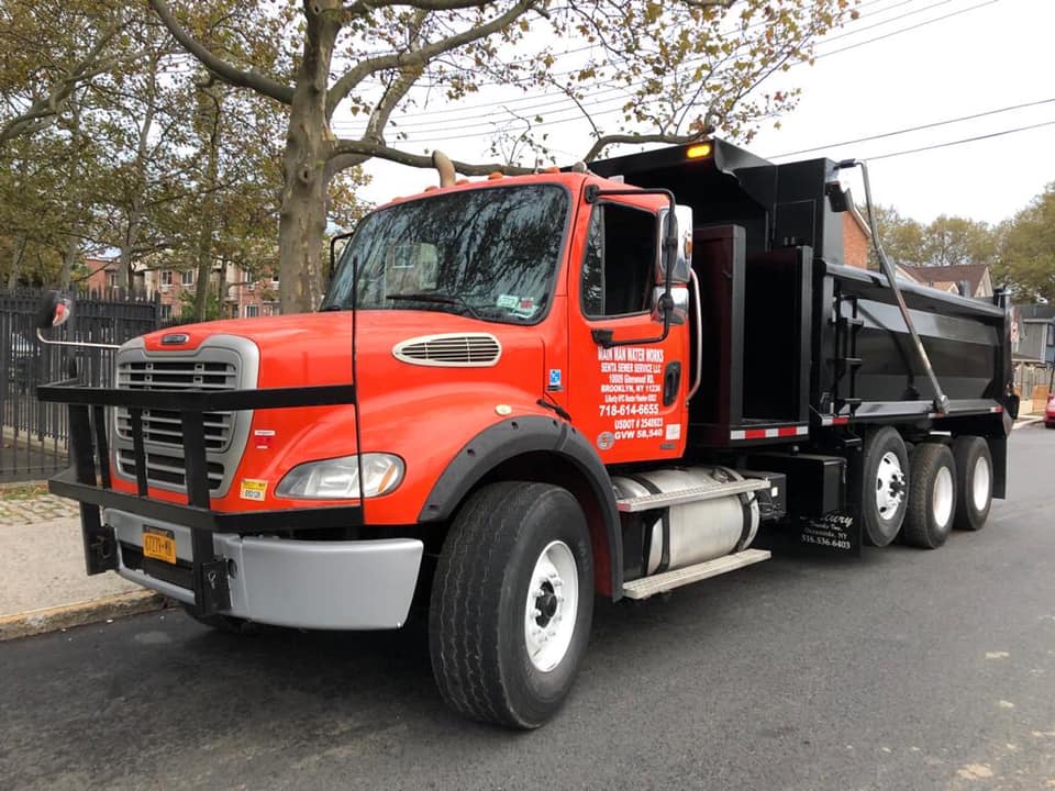 A red dump truck is parked on the side of the road