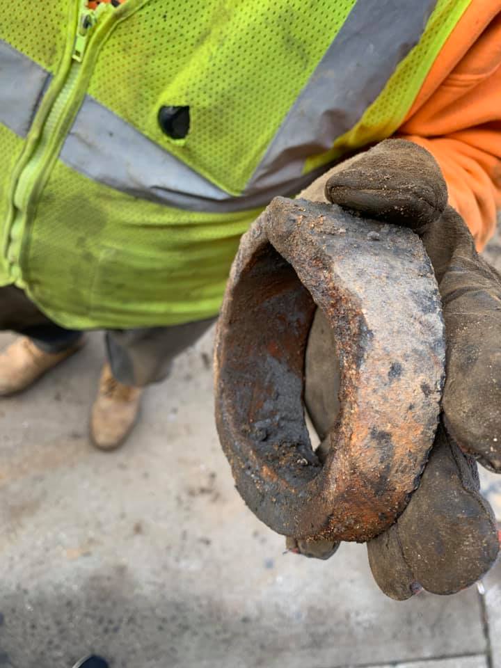 A person wearing gloves is holding a rusty object in their hand.
