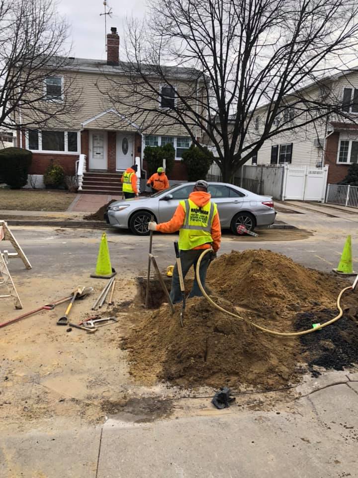 A man is digging a hole in the ground in front of a house.