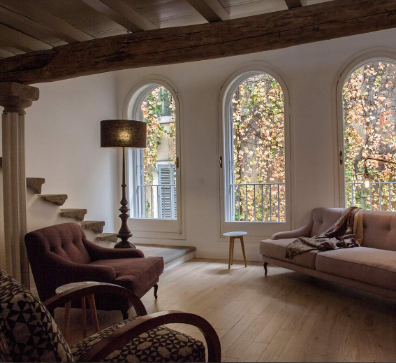 Soggiorno con divano nero, opere d'arte astratte, cucina, tavolo da pranzo e lampadario.