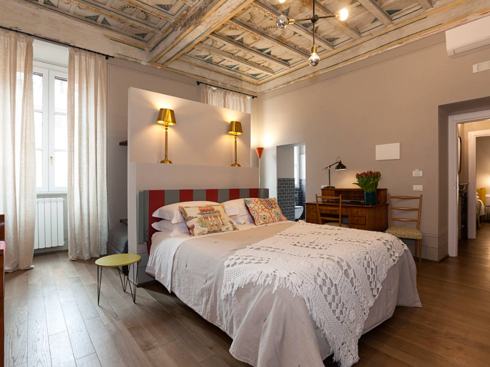 Soggiorno con opere d'arte astratte, divano blu, tavolo rotondo, sedie colorate e pavimento in legno.