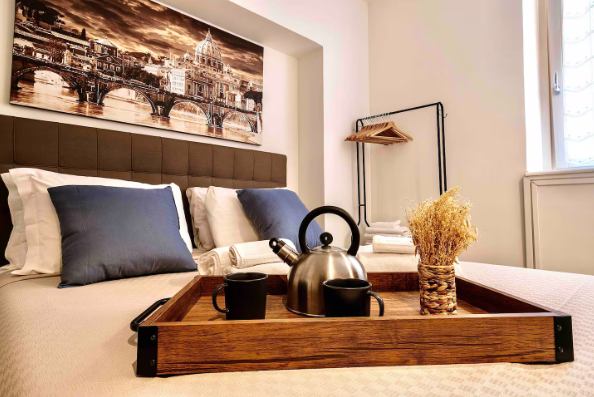 Camera da letto con vassoio con tè, tazze e decorazioni. Dipinto di un ponte, cuscini e un appendiabiti.