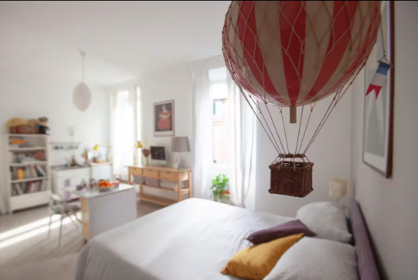 Camera da letto decorata con mongolfiere. Un palloncino rosso e bianco sopra il letto con cuscini.