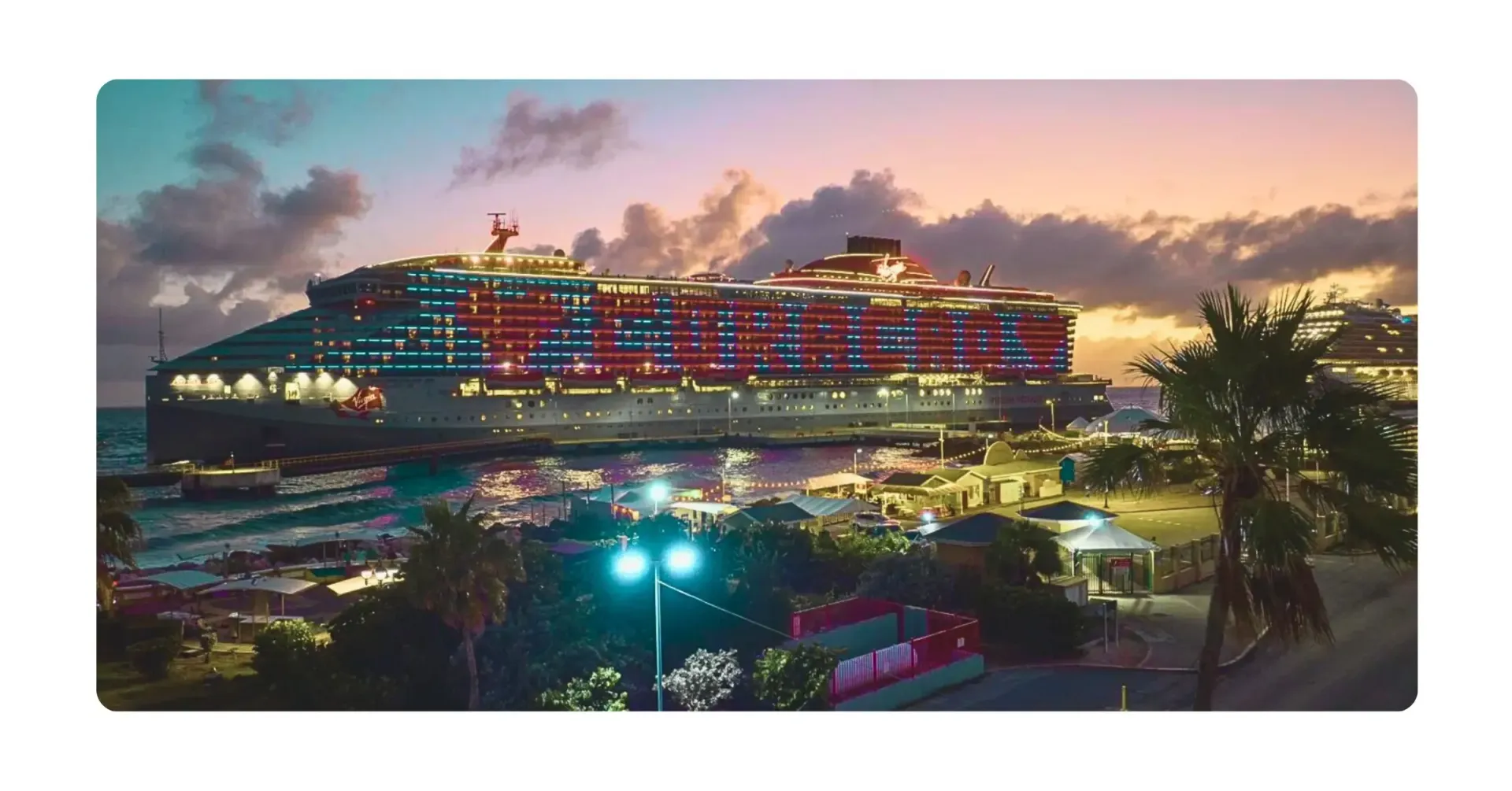 Cruise ship docked at Curacao port at dusk, illuminated with red and white lights