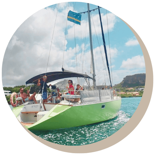 Green sailboat with people, sailing on water; Curacao flag.