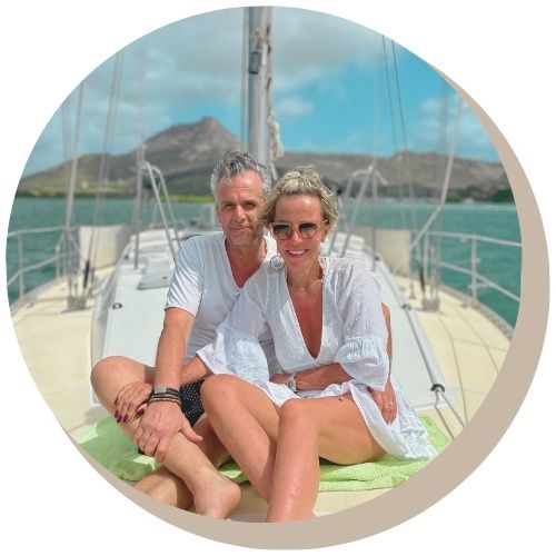 Sailboat on turquoise water; couple at helm.