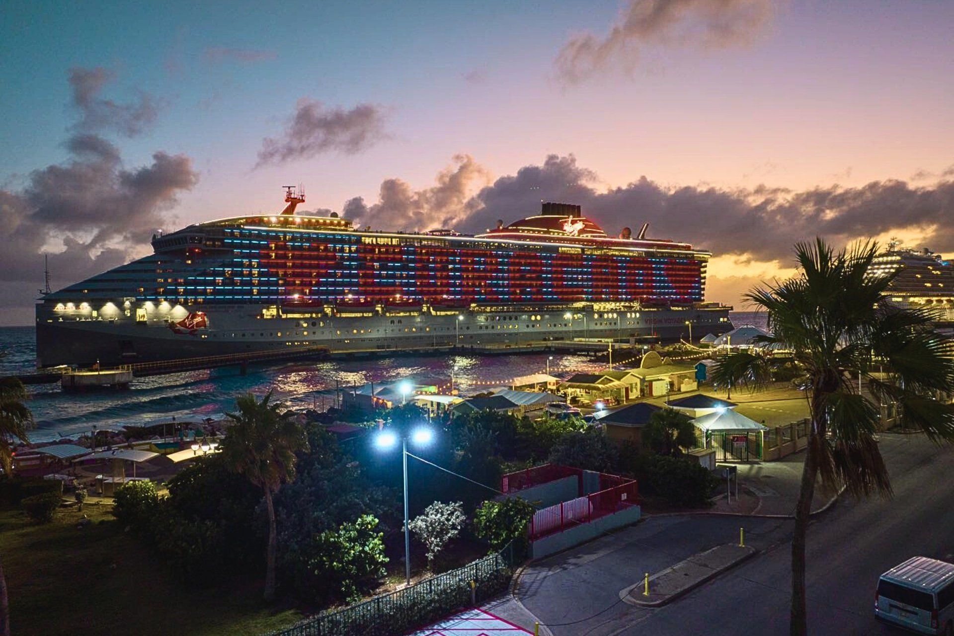 Cruise ship docked at Curacao port at dusk, illuminated with red and white lights