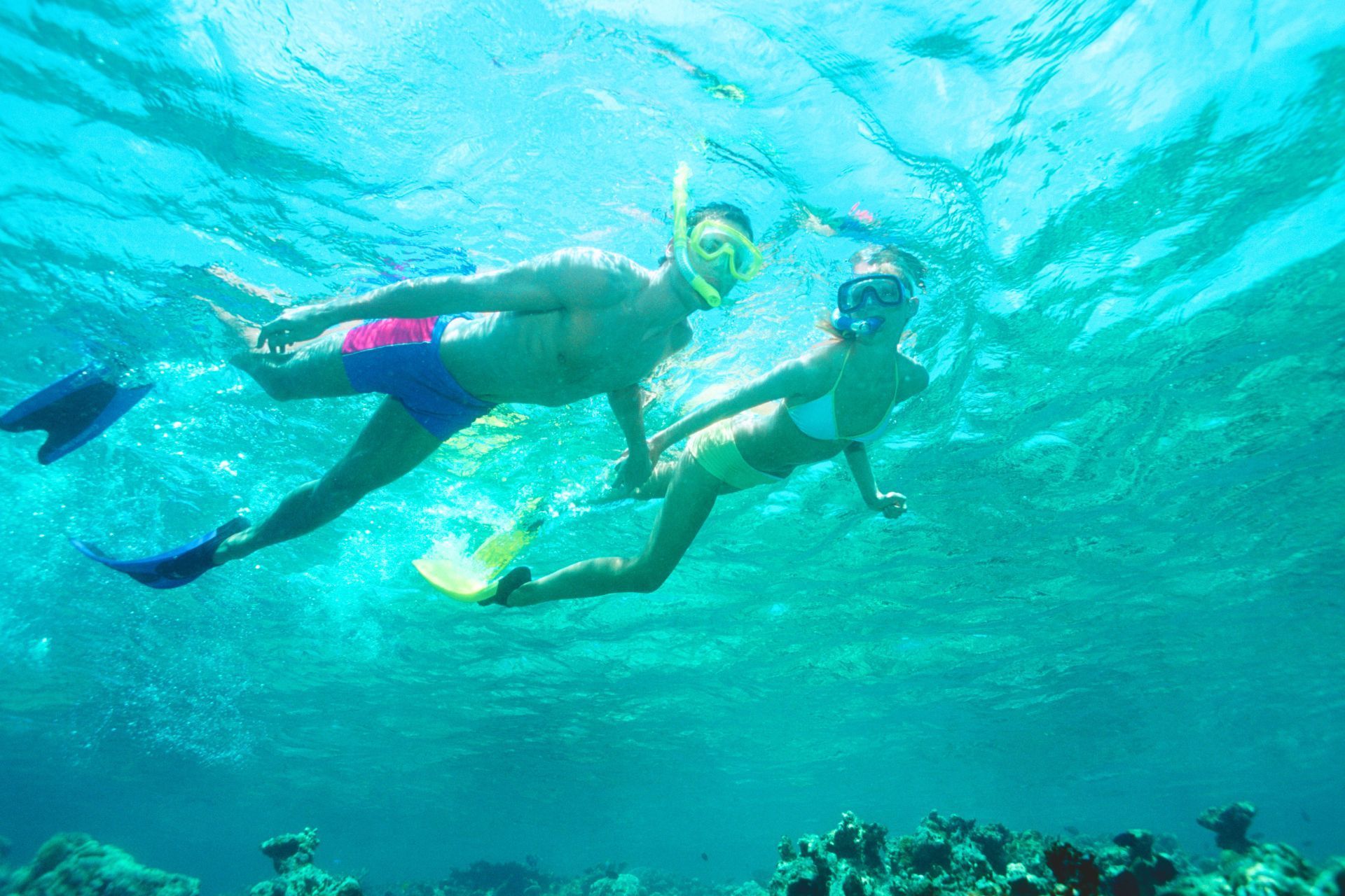 A man and a woman are swimming underwater in the ocean.