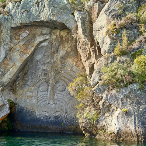 Red tram on tracks in front of a stone church with a steeple on a sunny day.