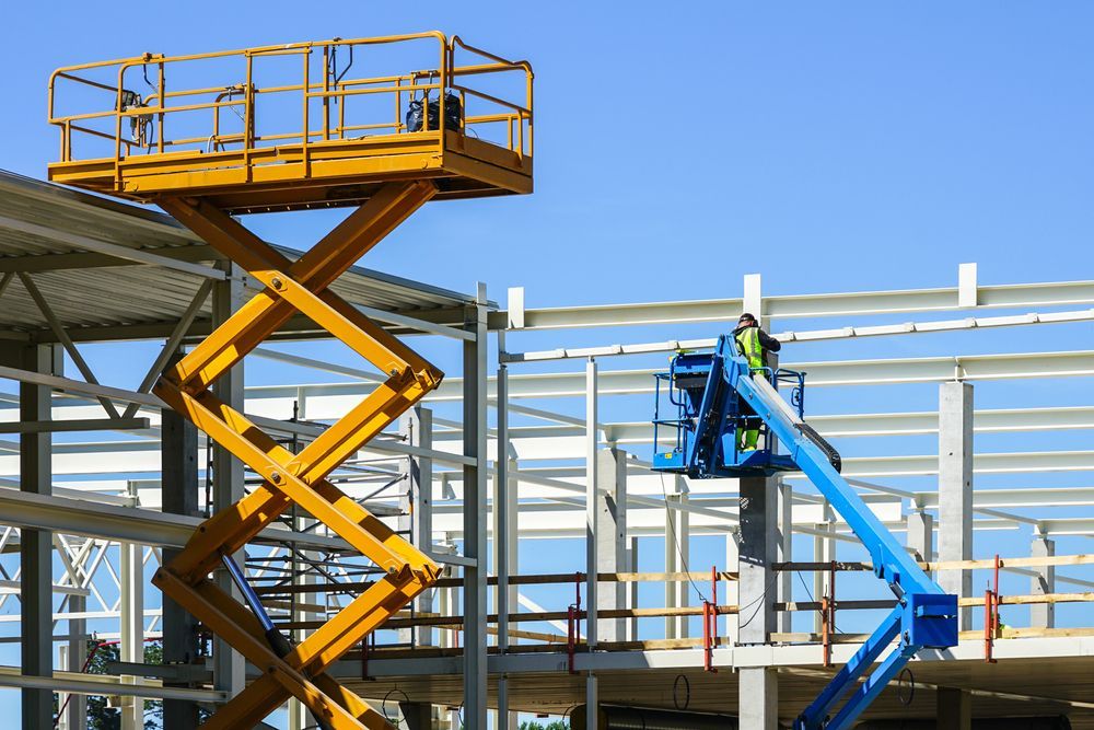 A Man is Working on a Scissor Lift at a Construction Site — Construction Services in Brisbane, QLD