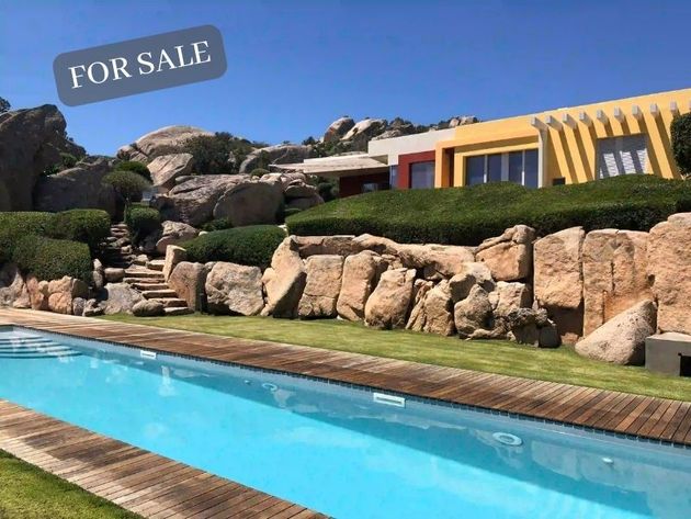 a large swimming pool in front of a house that is for sale