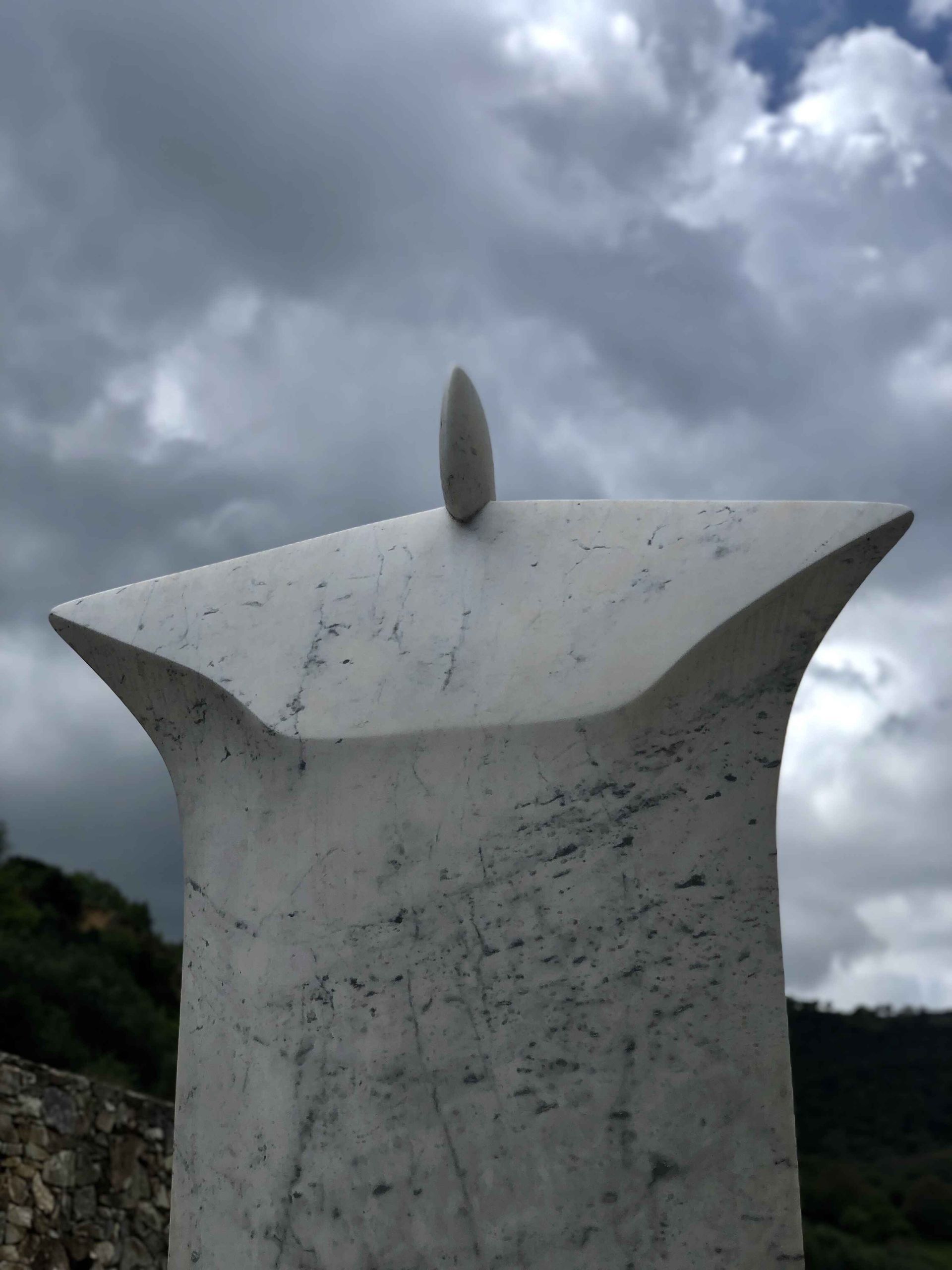 a statue with a cloudy sky in the background