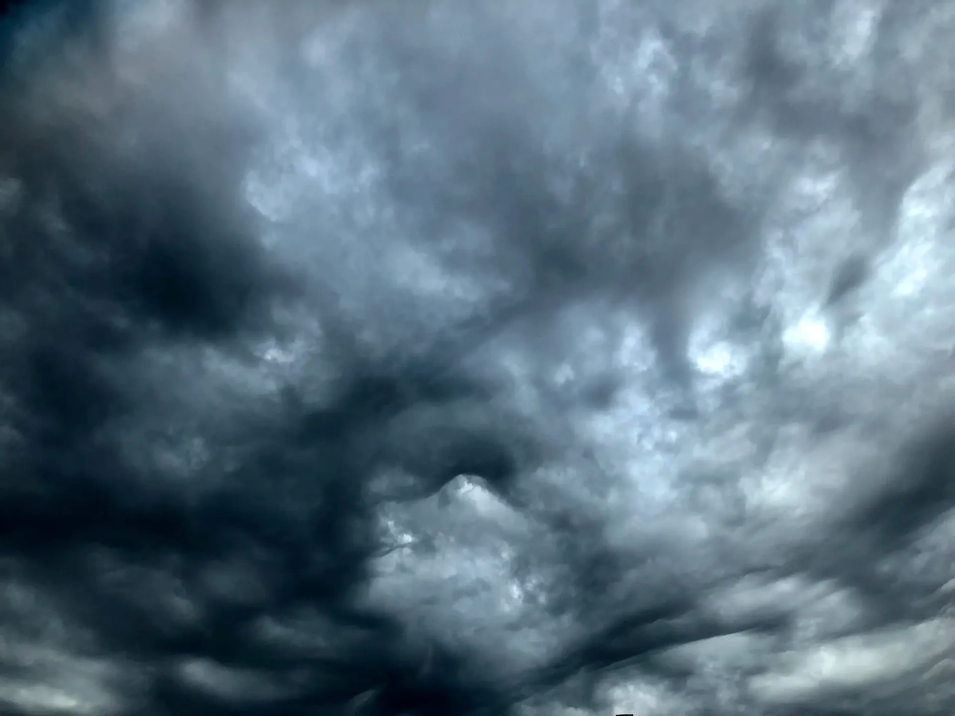 a dark cloudy sky with a few white clouds in it