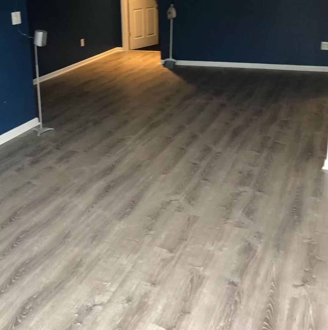 Gray wood-look flooring in a room with dark blue walls and white trim.
