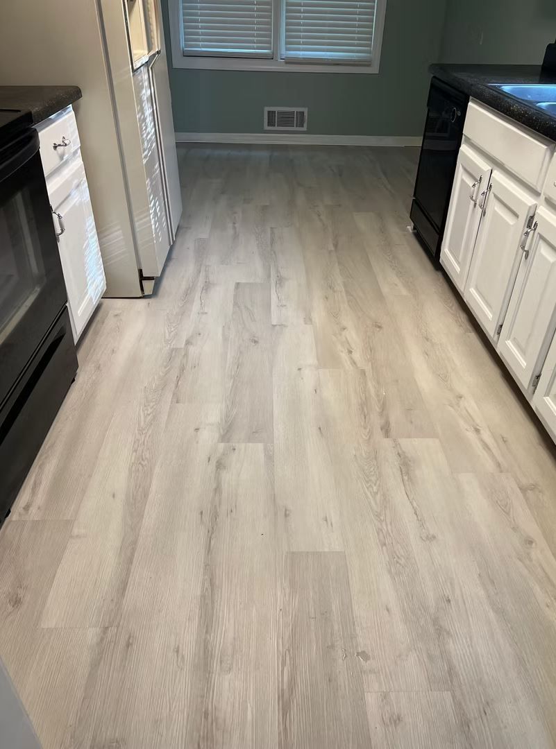 Kitchen with light gray wood-look flooring and white and black cabinets.