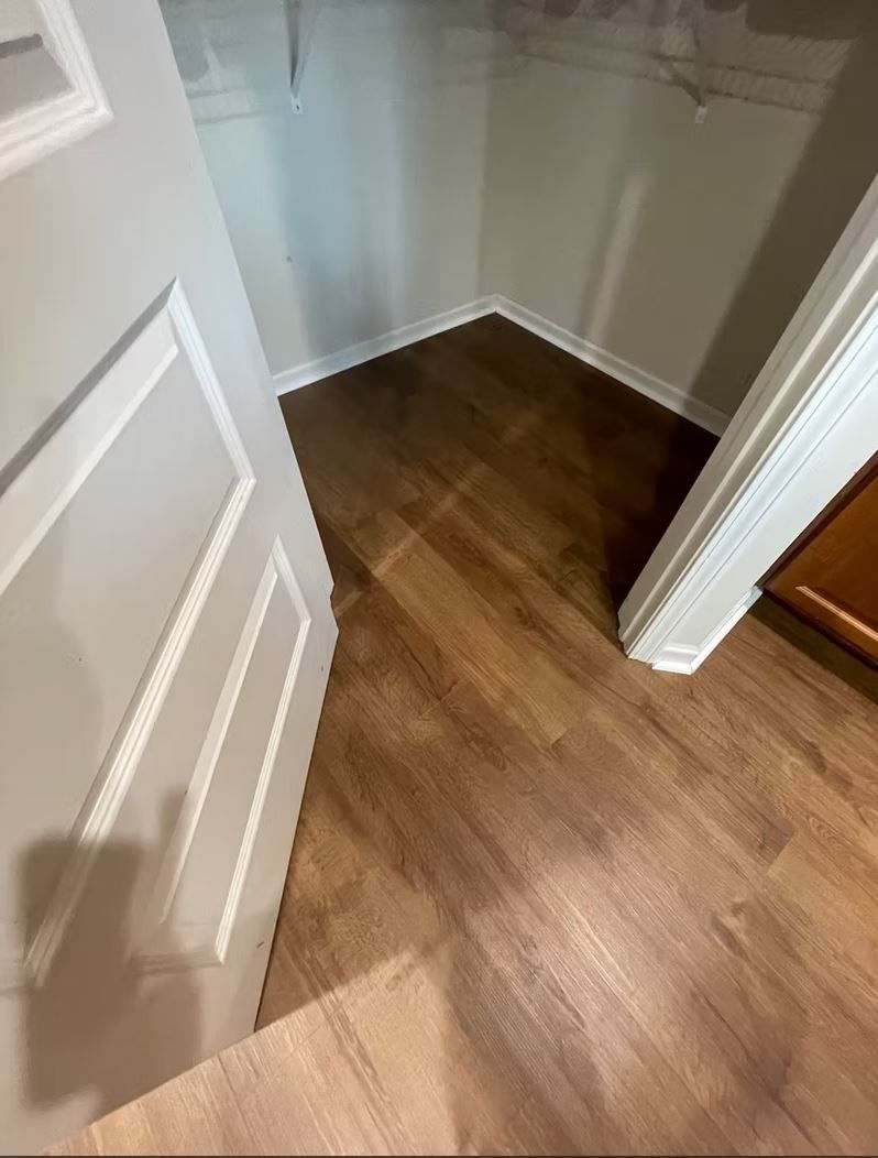 Doorway to a small closet with wood-look flooring. White trim and door.
