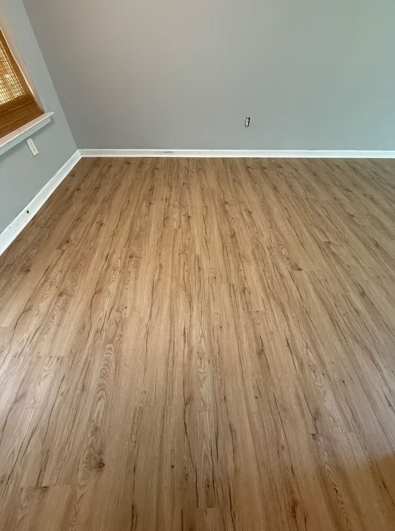 Light brown wood-look flooring in a room with gray walls and white trim.