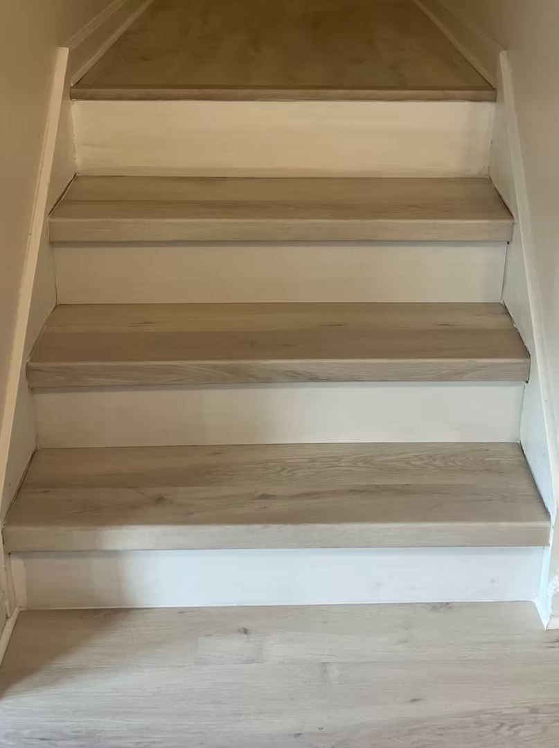 Staircase with light wood steps and white risers. The setting is indoors, likely a home.