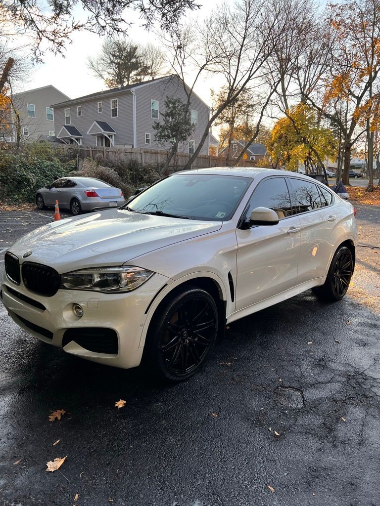 A white bmw x6 is parked in a parking lot.