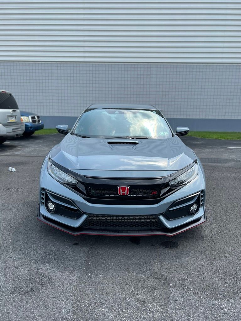 A honda civic type r is parked in a parking lot in front of a building.
