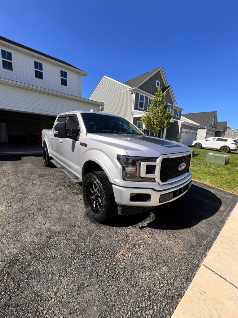 A white truck is parked in a driveway in front of a house.
