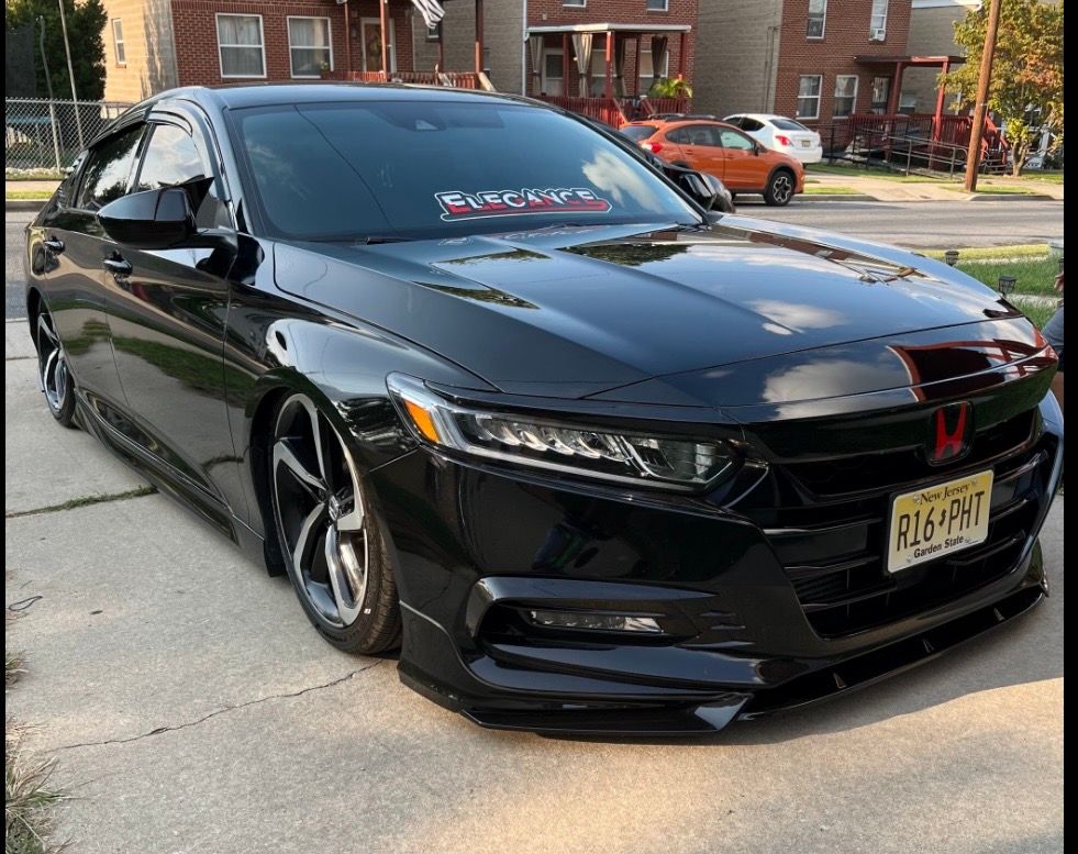 A black honda accord is parked on the side of the road.