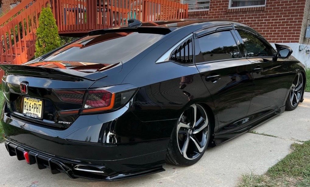 A black honda accord is parked in front of a brick house.