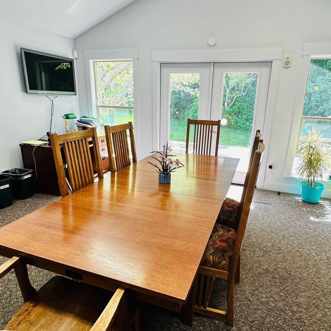 A dining room with a long wooden table and chairs
