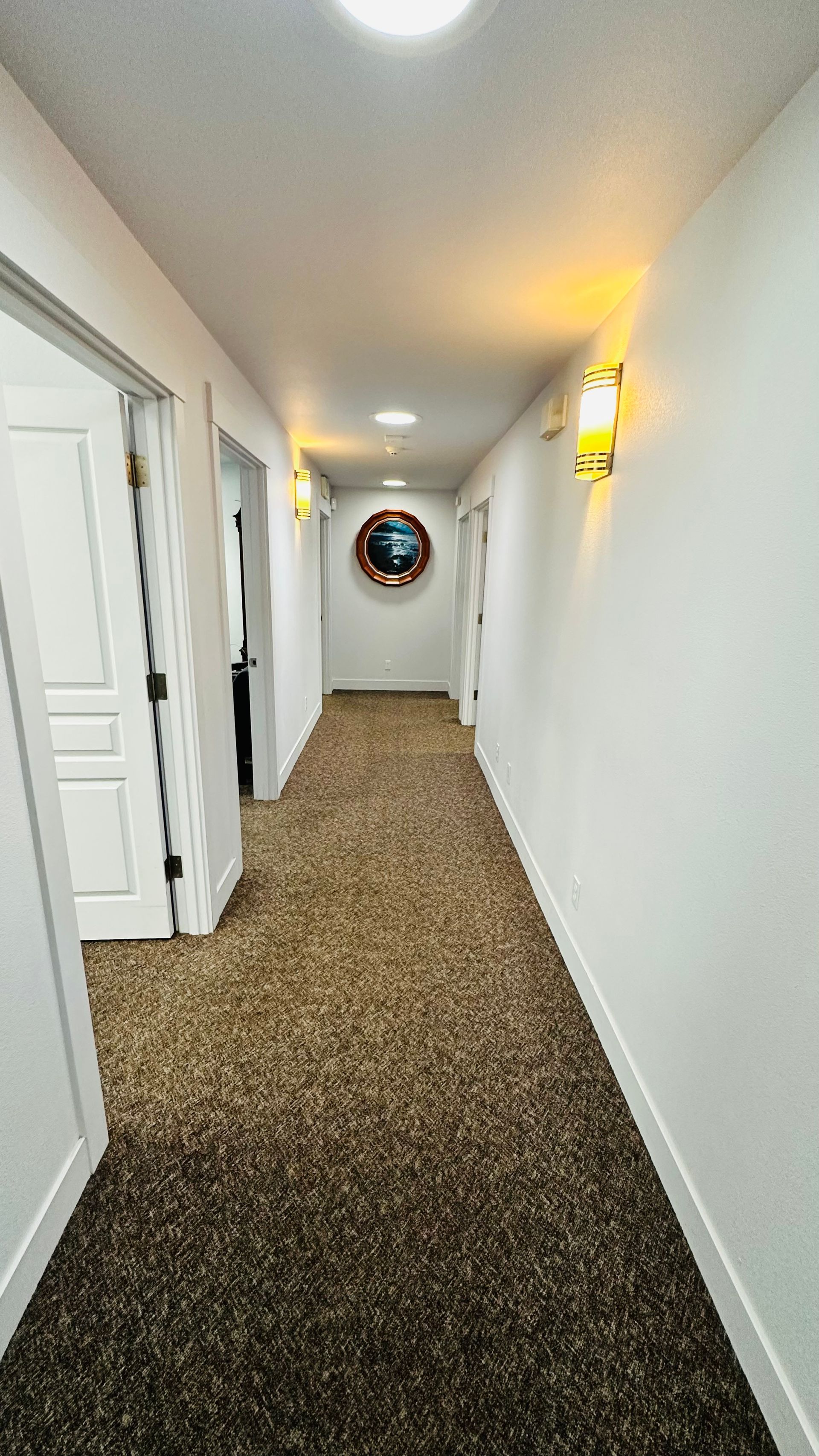 A long hallway with a mirror on the wall and a carpeted floor.