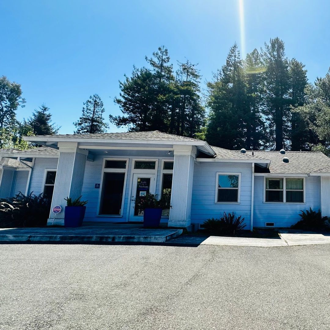A white house with a gray roof is for sale