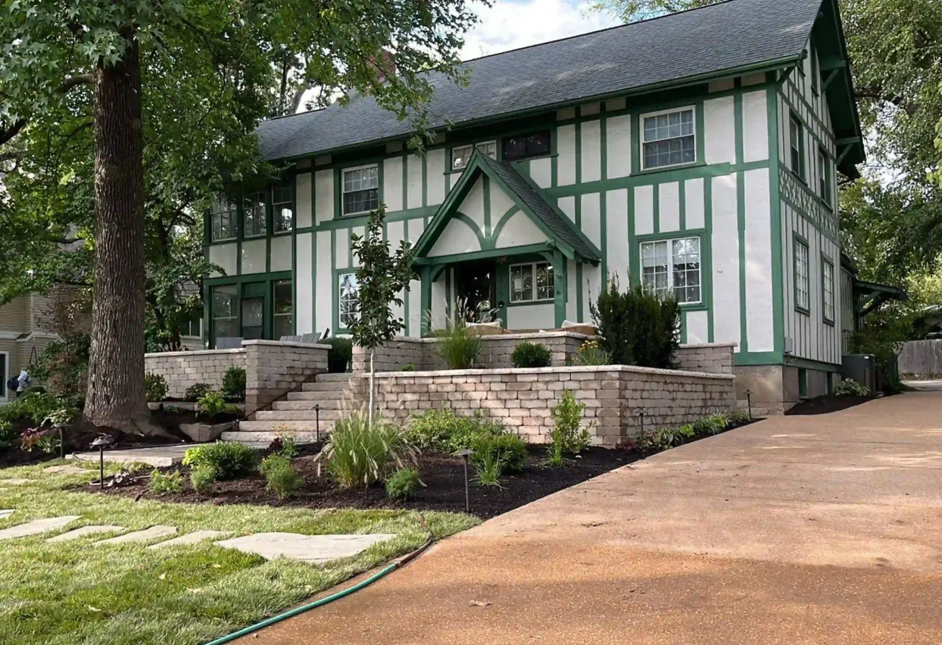 A white and green house with a driveway leading to it