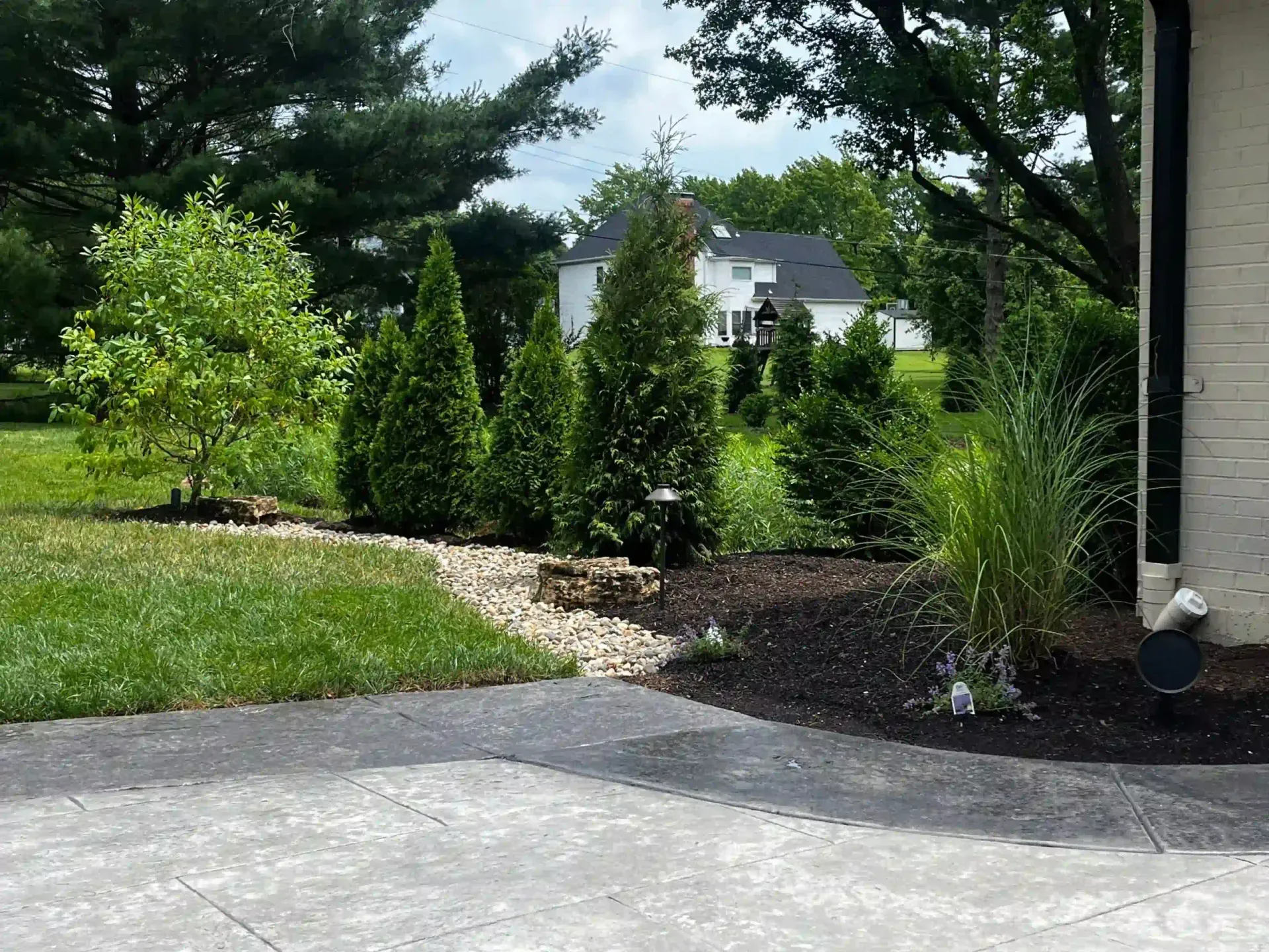 A driveway leading to a house with trees in the background.