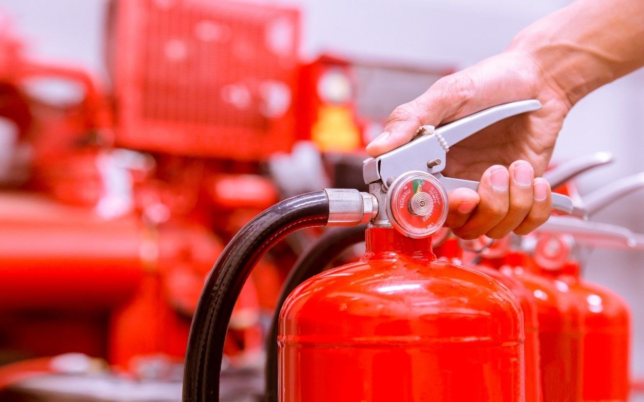 A person is holding a red fire extinguisher in their hand.