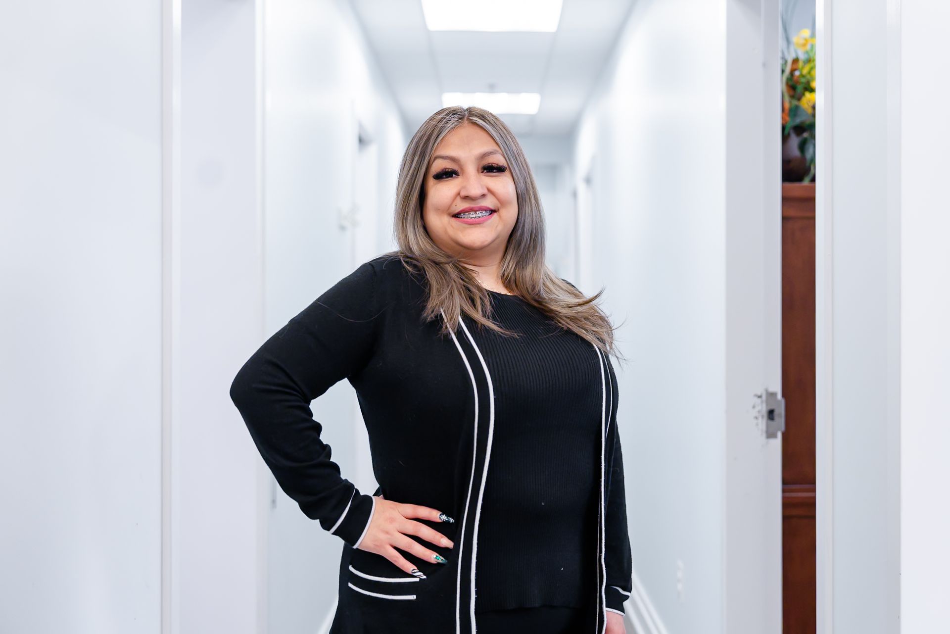 Man in black scrubs smiles with arms crossed in front of