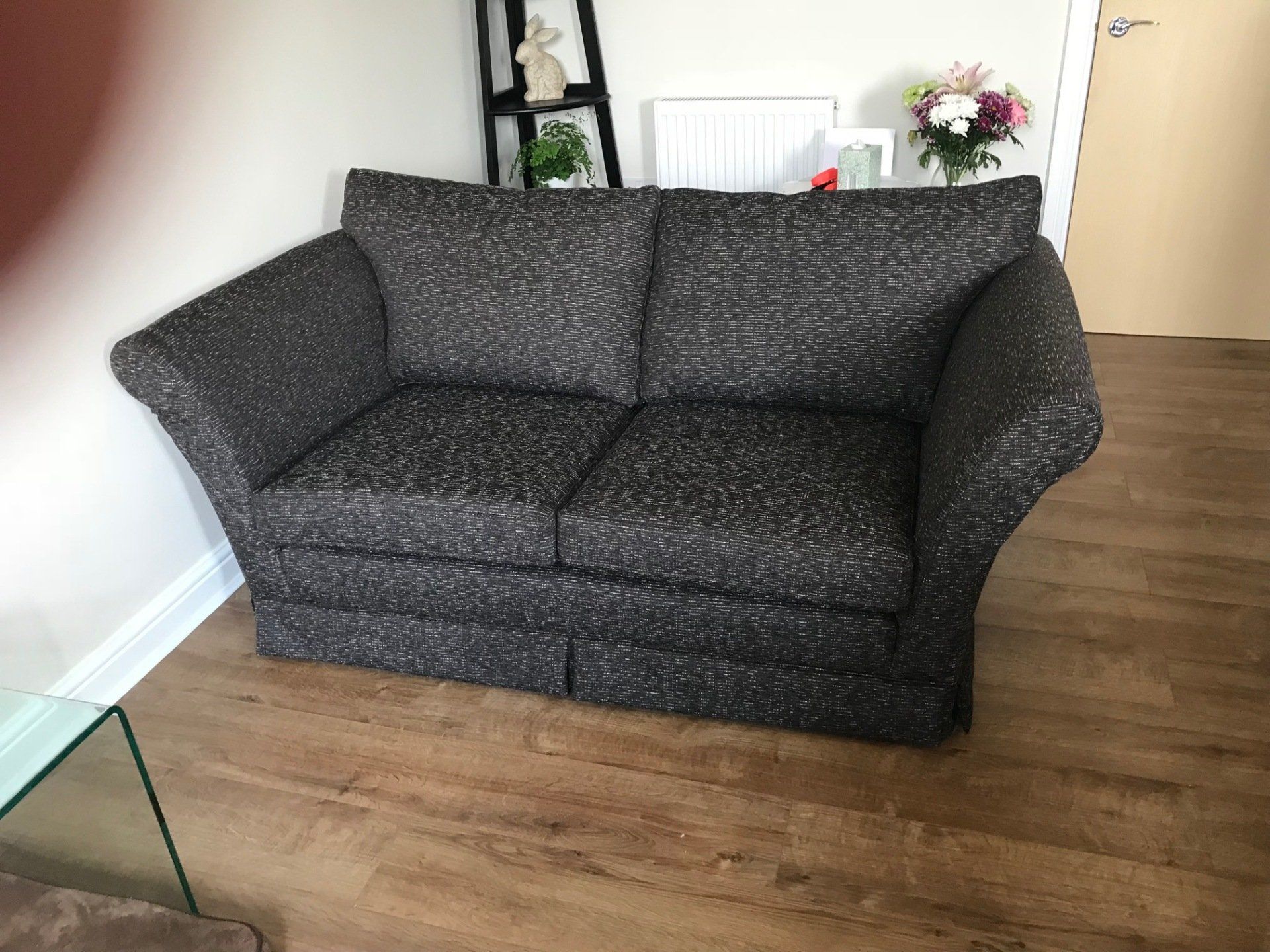 A small dark patterned sofa on a wooden floor