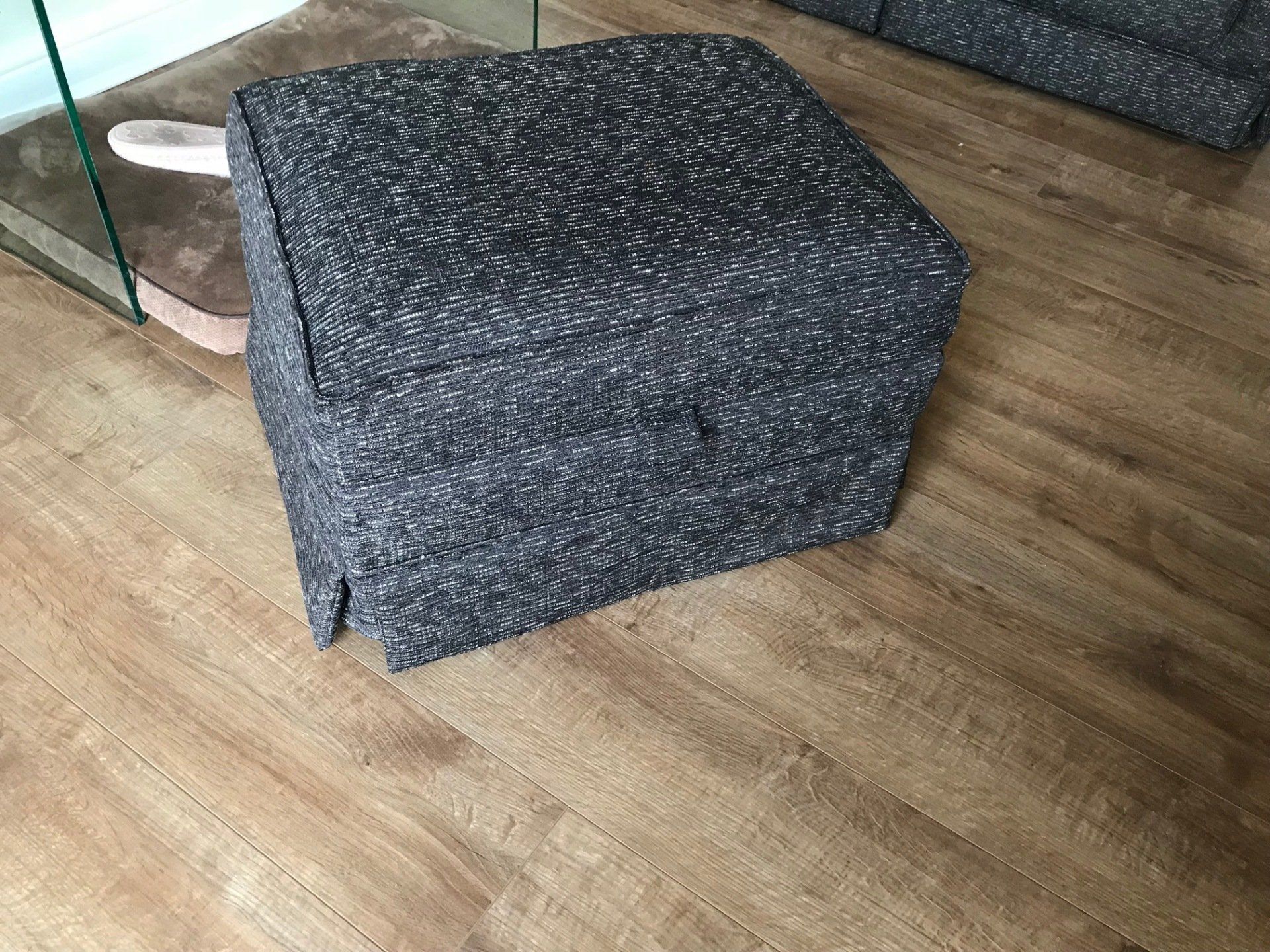 A dark blue upholstered footstool