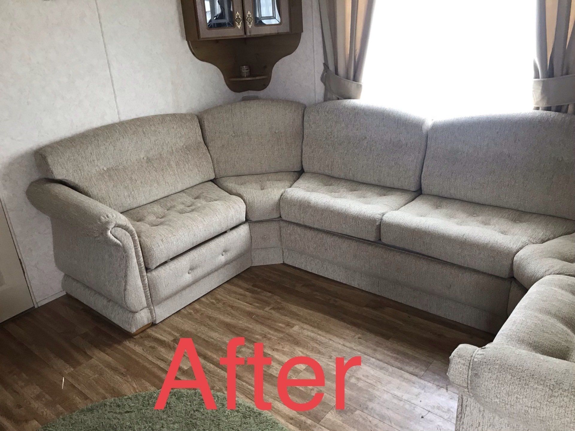 Corner of a grey corner set in front of a window with a wooden floor