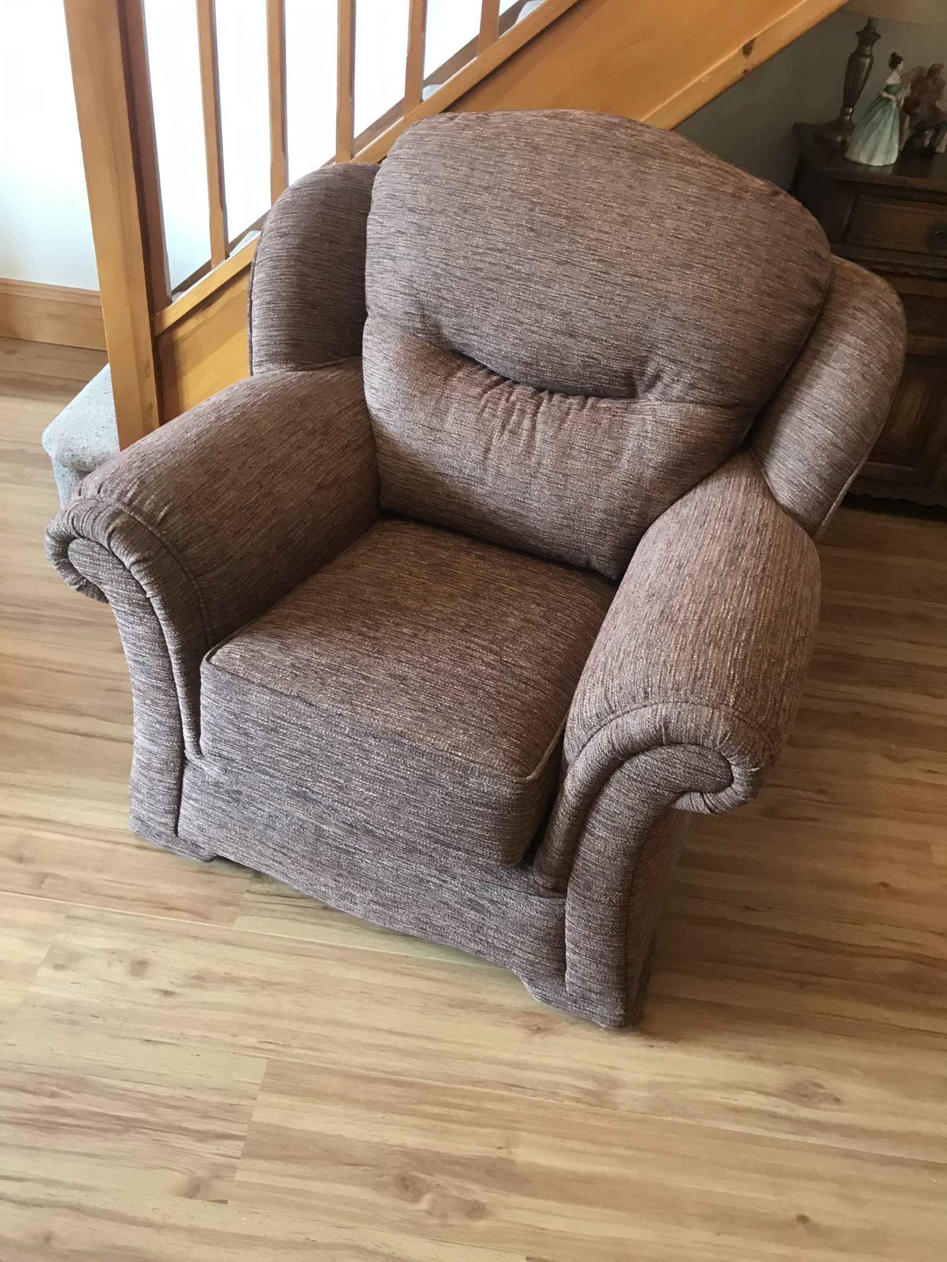 Grey armchair on a wooden floor in front of stairs