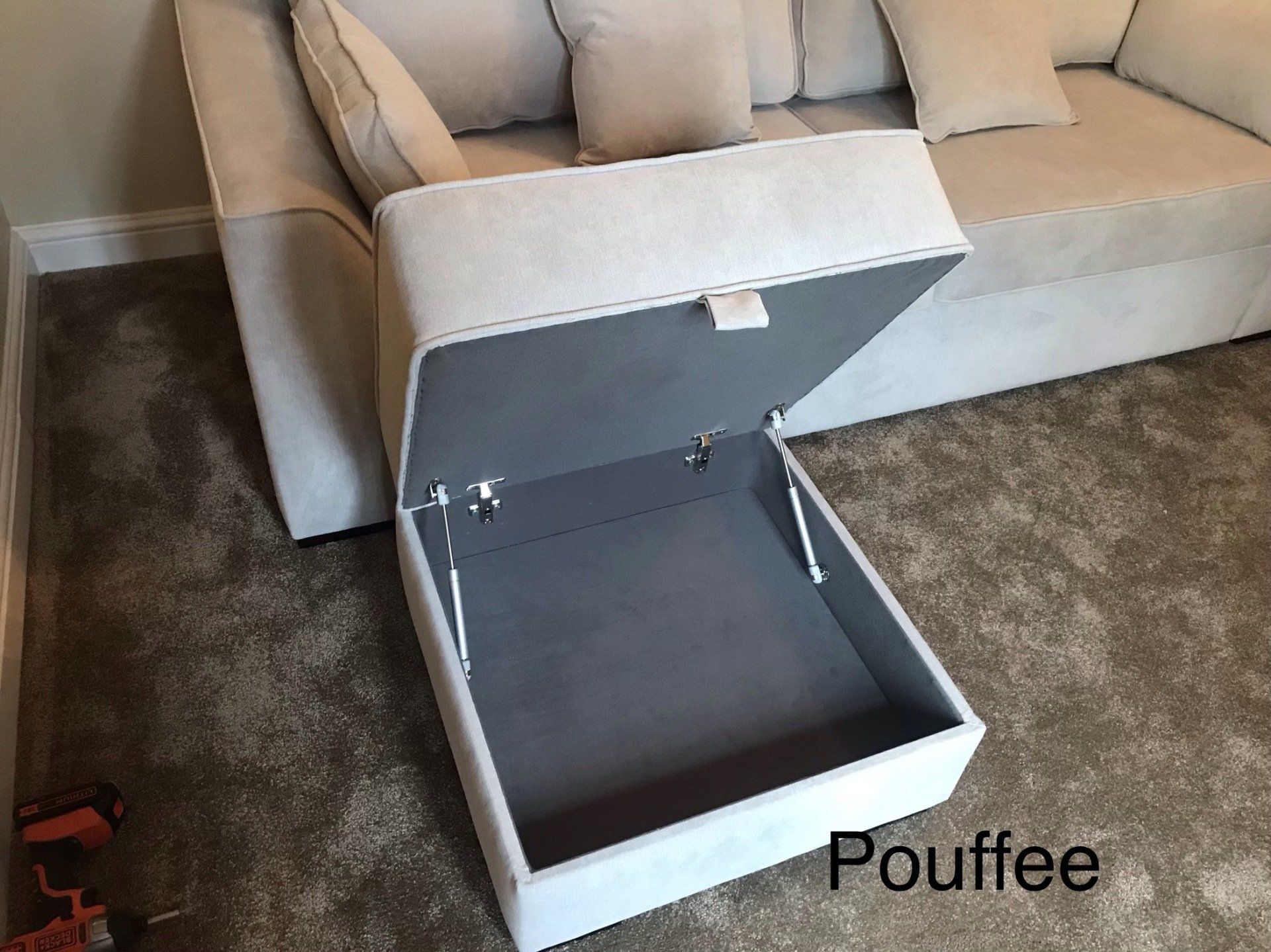 A footstool with storage inside, opened to show it is empty