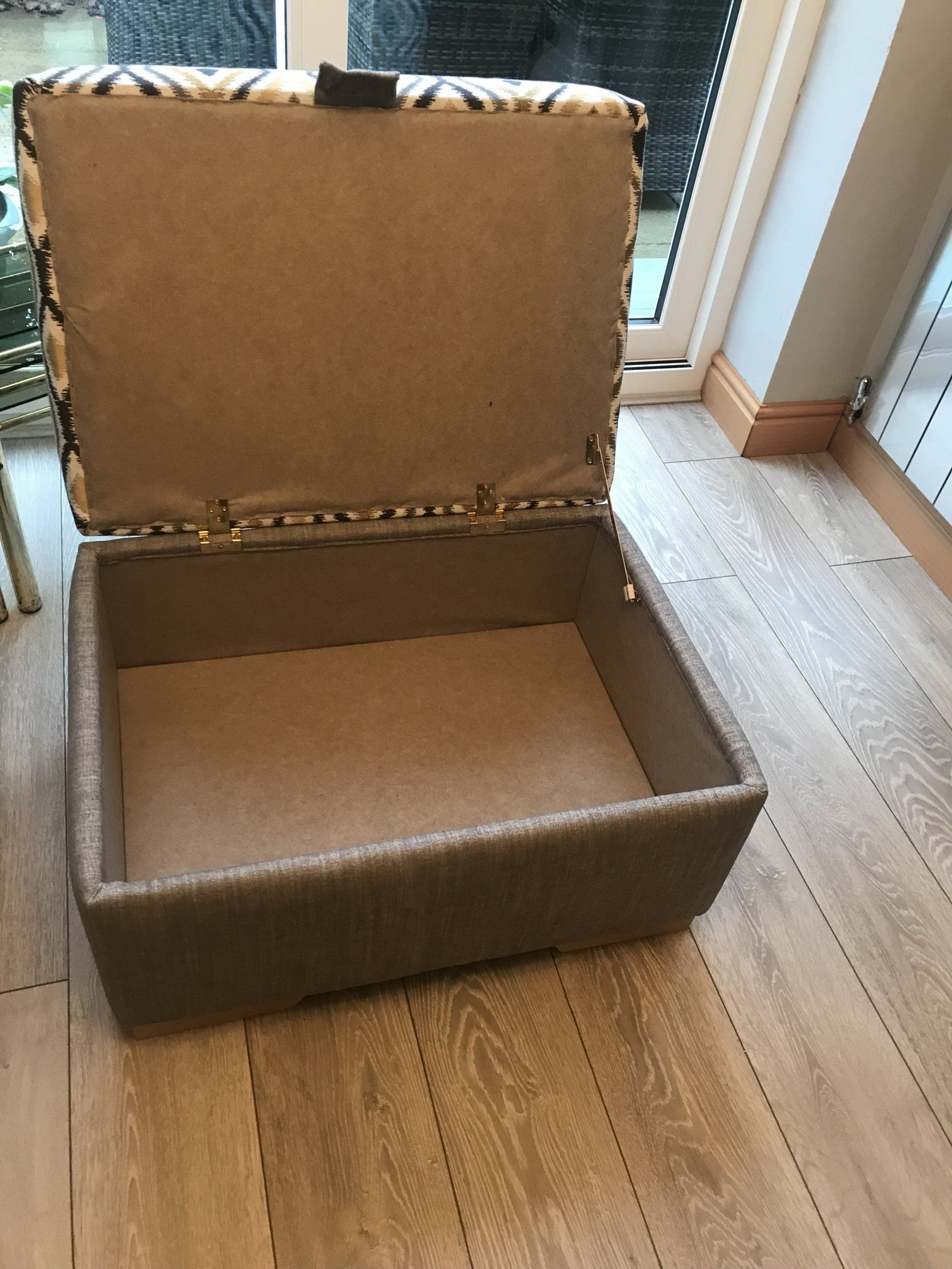 An open and empty storage box on a wooden floor