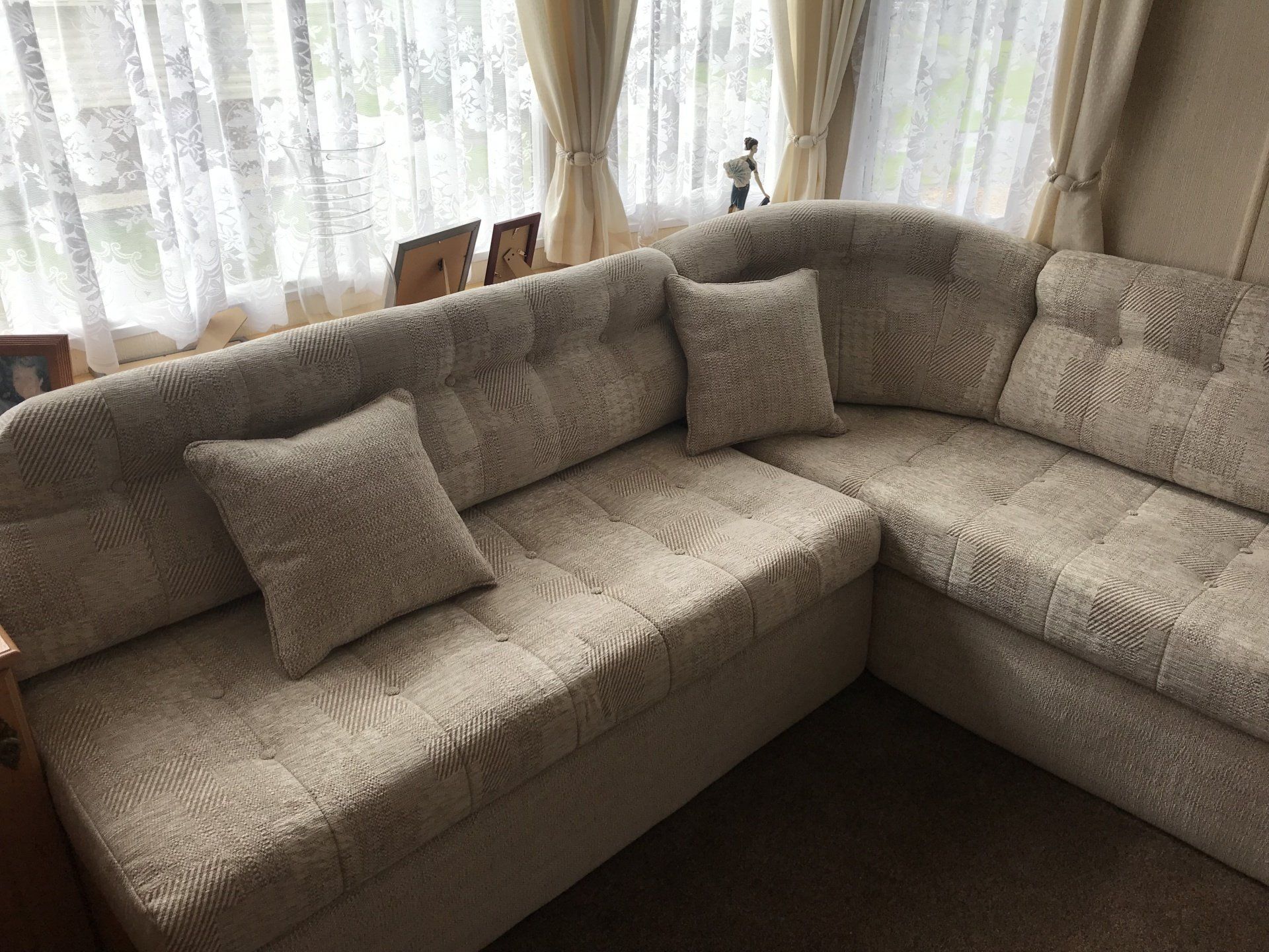 Corner set with cushions in front of a window with a net curtain